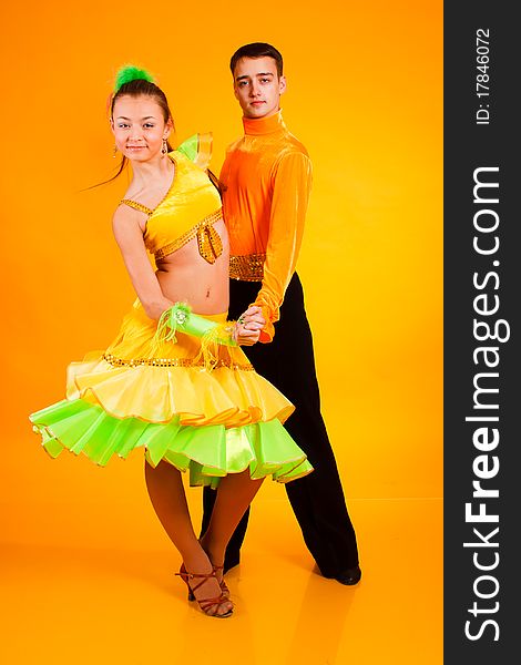 Charming young  pair in good-looking suits on a yellow background