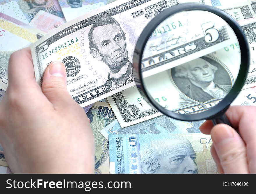 Woman checks her US five dollar bill with Magnifying glass. Woman checks her US five dollar bill with Magnifying glass