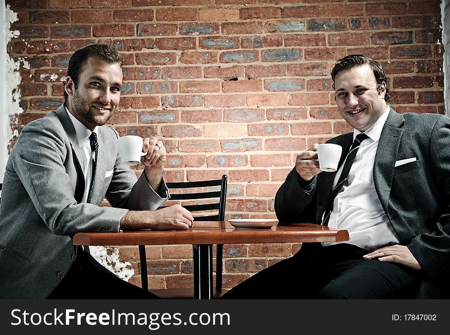 Business partners smile towards camera with coffee in hand. Business partners smile towards camera with coffee in hand