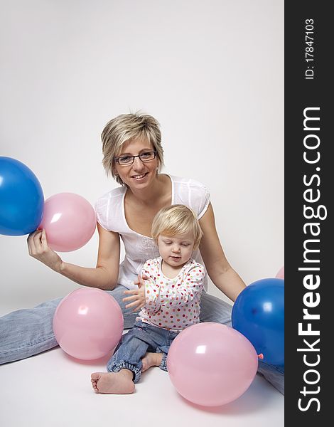 Portrait of cute girl with her mother with pink and blue balloons having fun at the party. Portrait of cute girl with her mother with pink and blue balloons having fun at the party