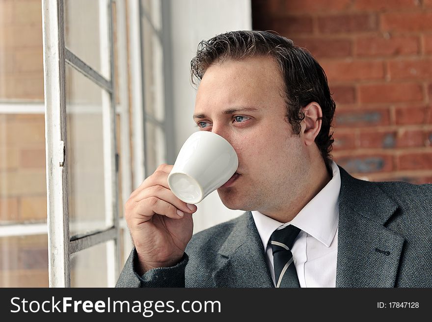 Old style man with coffee at the window while wearing suit. Old style man with coffee at the window while wearing suit