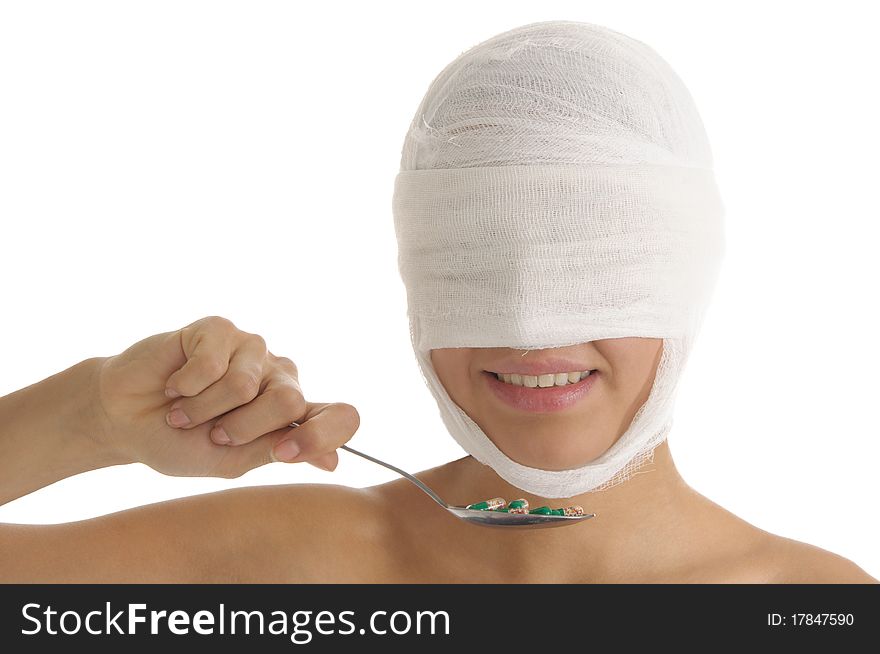 Young woman with bandaged head with tablets on spoon isolated in white