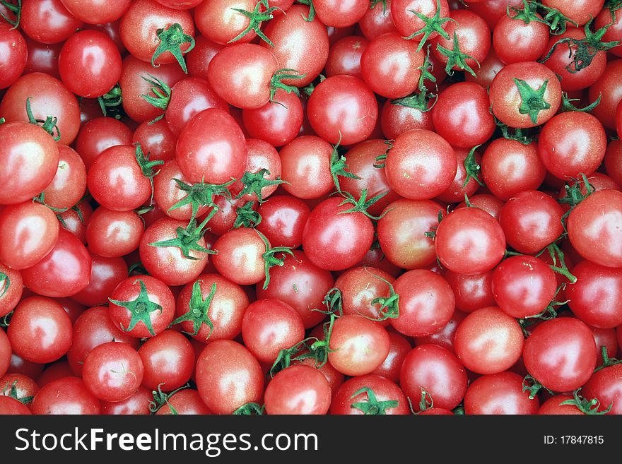 Many deep red tomatoes with green stems, full with antioxidants