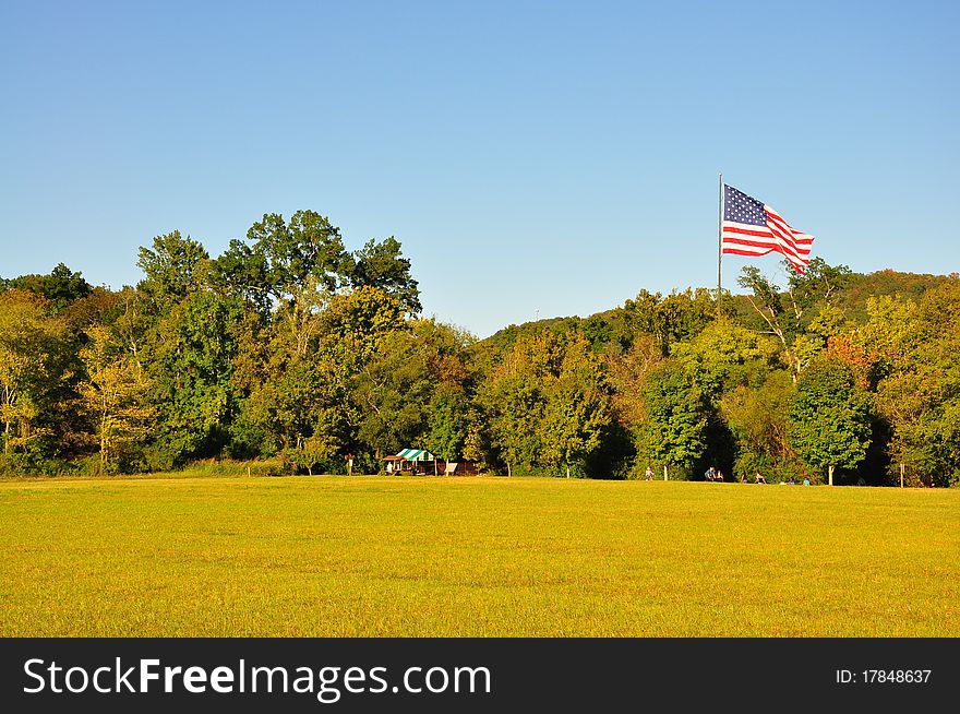 An empty field with a flag in the background. An empty field with a flag in the background
