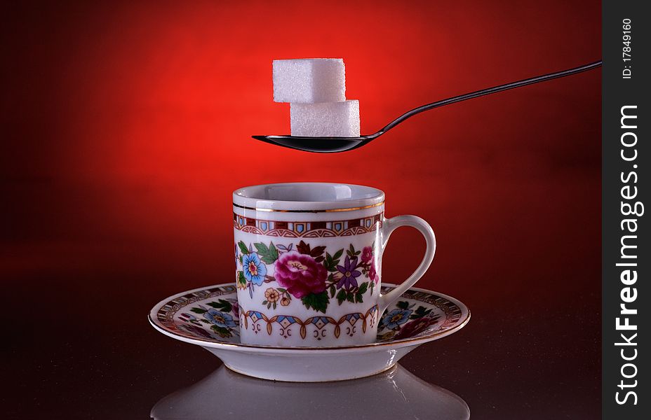 Cup of coffee and sugar on a dark red background