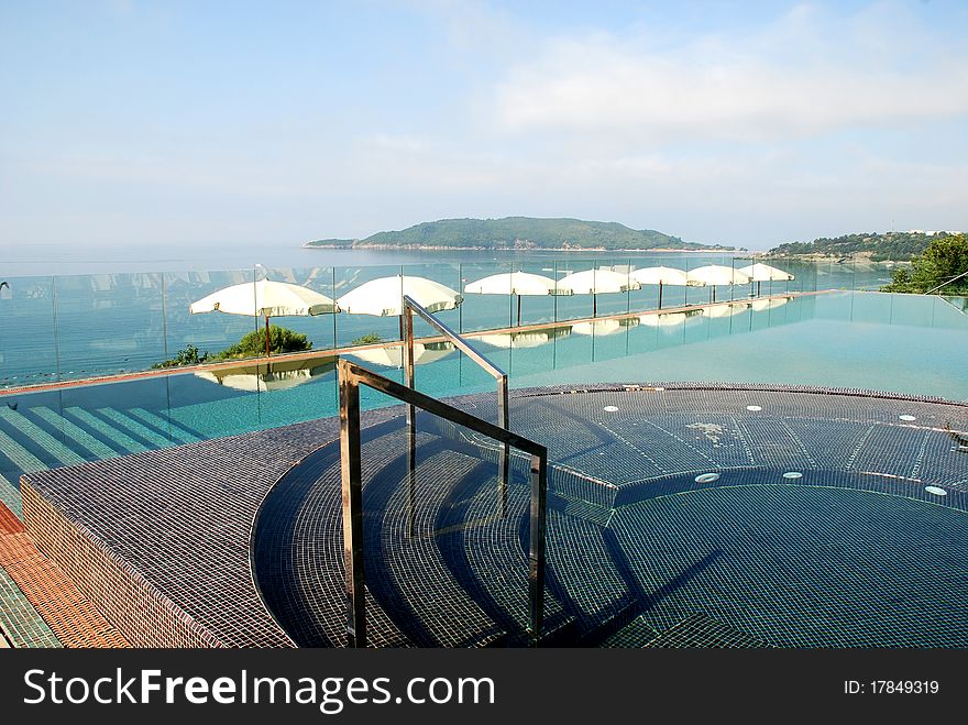 Beautiful blue fresh infinity swimming pool with steps in a luxury hotel  with Mediterranean sea views. Beautiful blue fresh infinity swimming pool with steps in a luxury hotel  with Mediterranean sea views