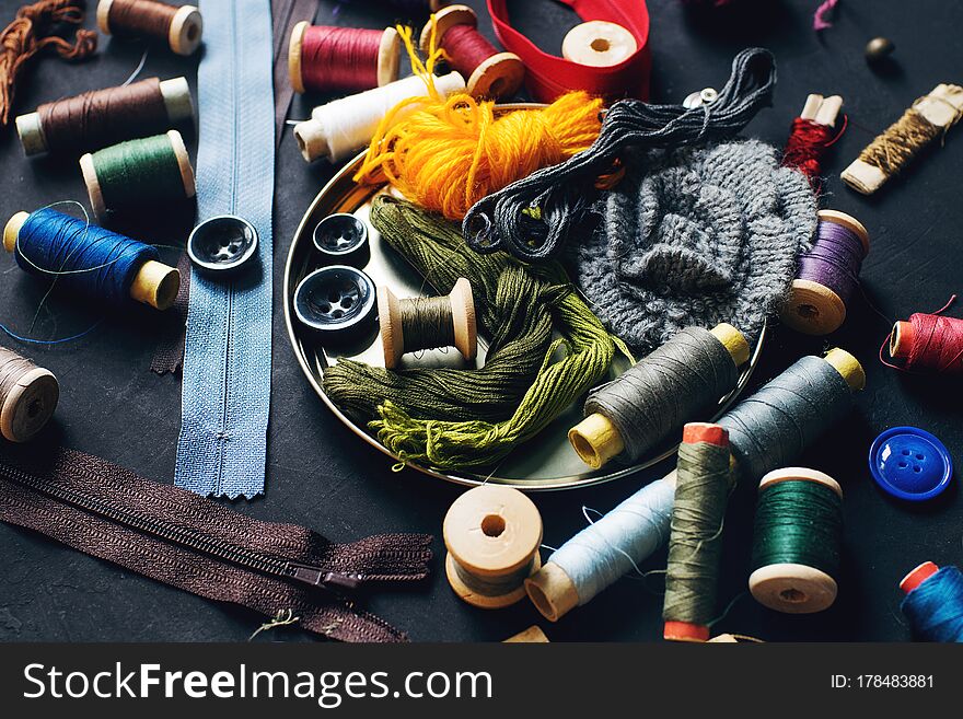 Sewing kit accessories for handicraft or needlework on dark stone table, colorful threads, home hobby and quarantine concept,  selective focus