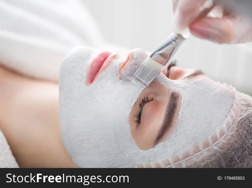 Face peeling mask, spa beauty treatment, skincare. Woman getting facial care by beautician at spa salon.