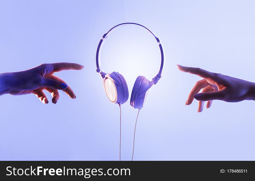 Hands of guy and girl reach for headphones, free space
