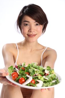 Japanese Girl Holds Out A Plate Of Green Salad Royalty Free Stock Image
