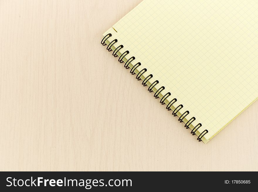 Yellow note book with lots of room for your text or image on a wooden desk