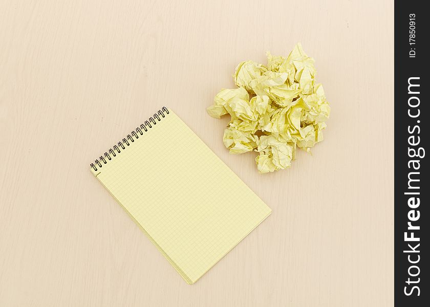 Notebook and crumpled paper on wooden table