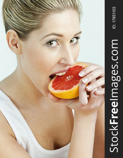 Portrait of young woman eating grapefruit