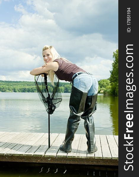Fishing woman with landing net standing on pier. Fishing woman with landing net standing on pier