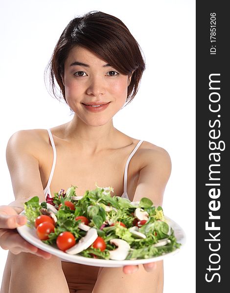 Japanese girl holds out a plate of green salad