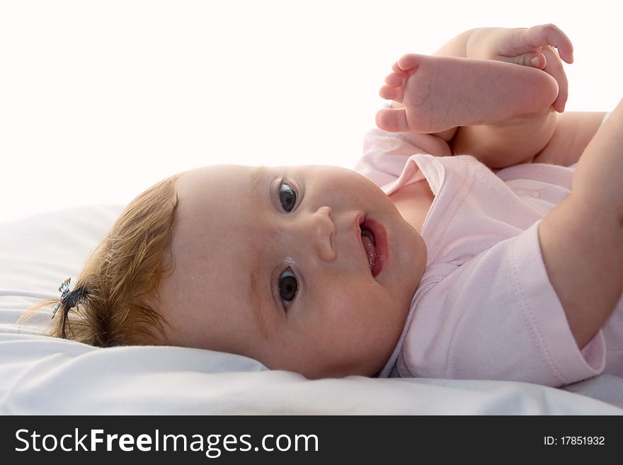 The happy baby lies on bed. Age of 0-6 months. A white background