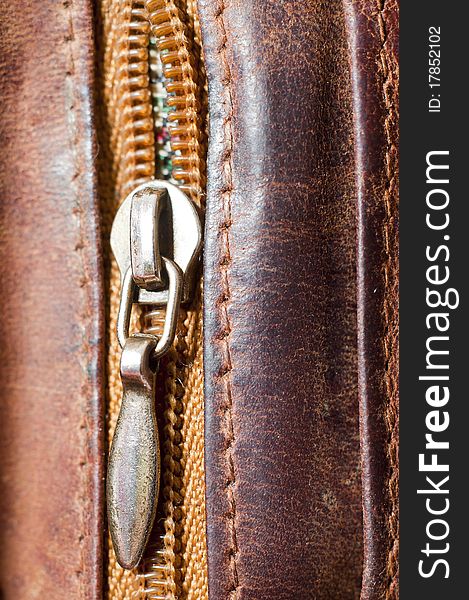 An image of zipper on brwon leather. An image of zipper on brwon leather