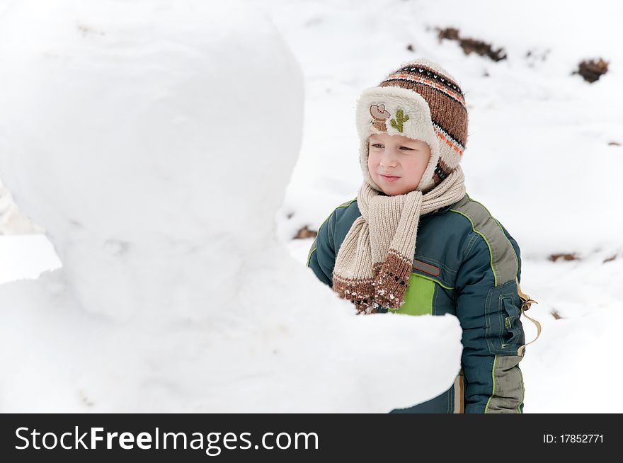 The child thoughtfully looks at the snowman. The child thoughtfully looks at the snowman