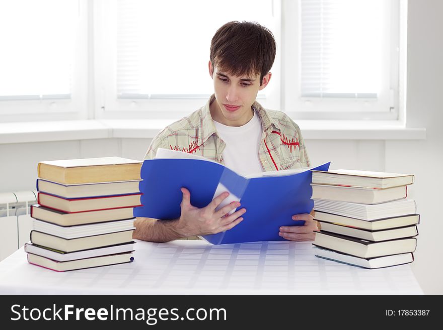 Student sits at a table and read documents. Student sits at a table and read documents