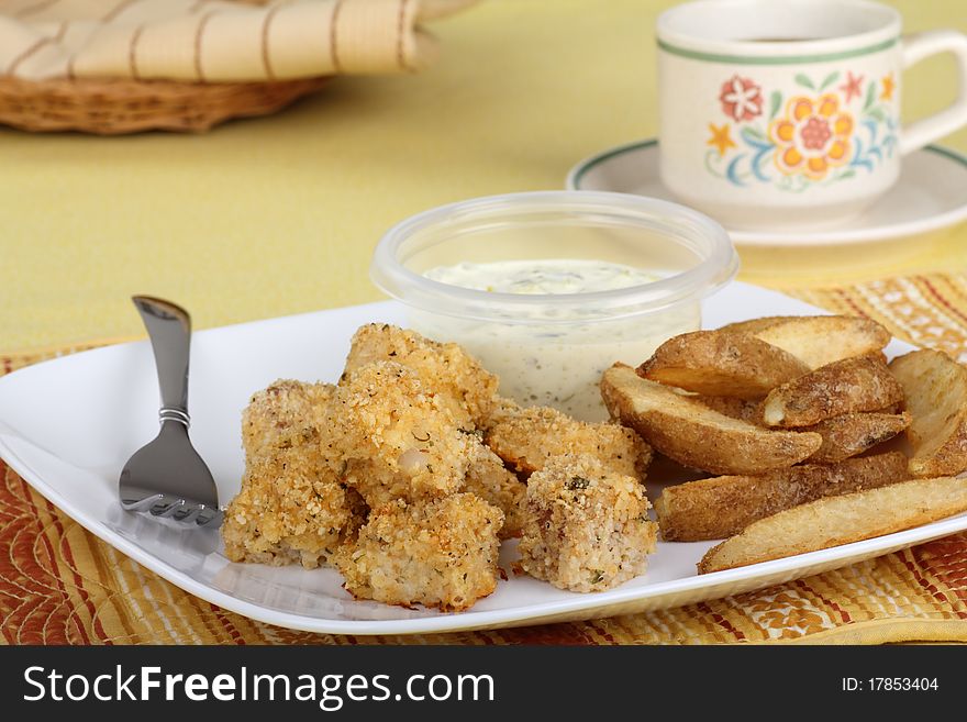 Fish nuggets with potatoes and tartar sauce on a plate. Fish nuggets with potatoes and tartar sauce on a plate