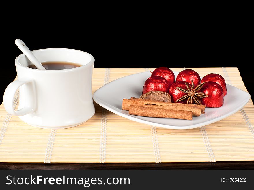 A cup of tea on the table with sweets, cinammon, anise and nutmed. A cup of tea on the table with sweets, cinammon, anise and nutmed.