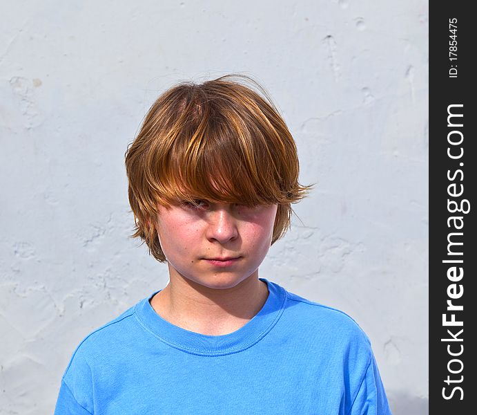Portrait of an unhappy young boy in sunlight with white wall. Portrait of an unhappy young boy in sunlight with white wall