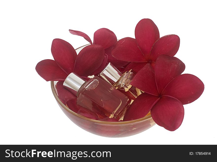 Spa concept - red plumeria and perfume bottles in bowl