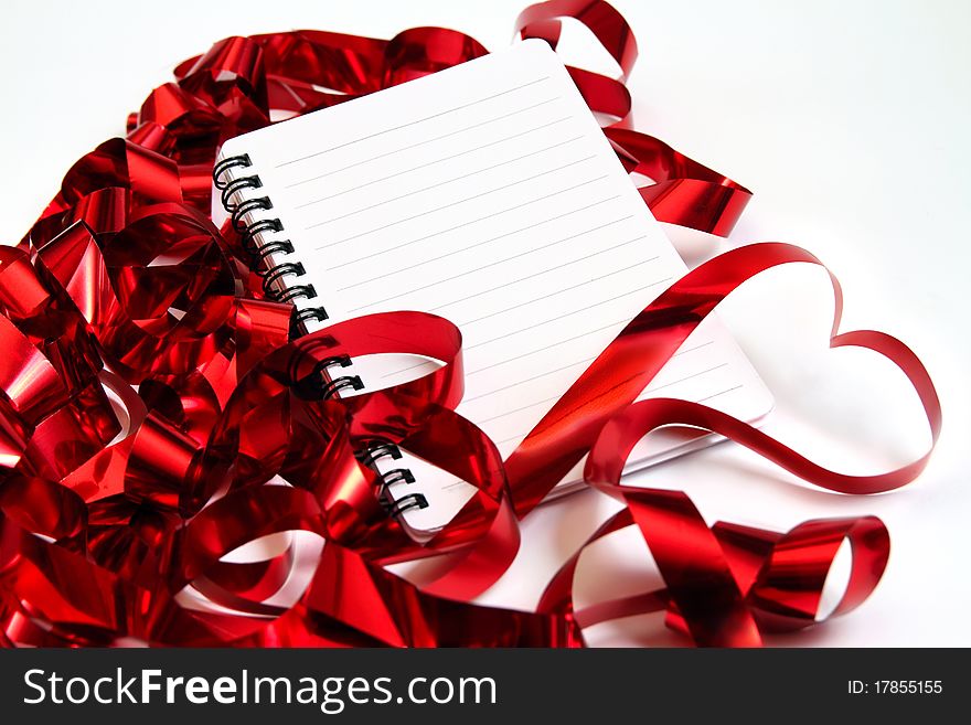 Valentine background with writing-pad and shiny red ribbons in the shape of heart. Valentine background with writing-pad and shiny red ribbons in the shape of heart