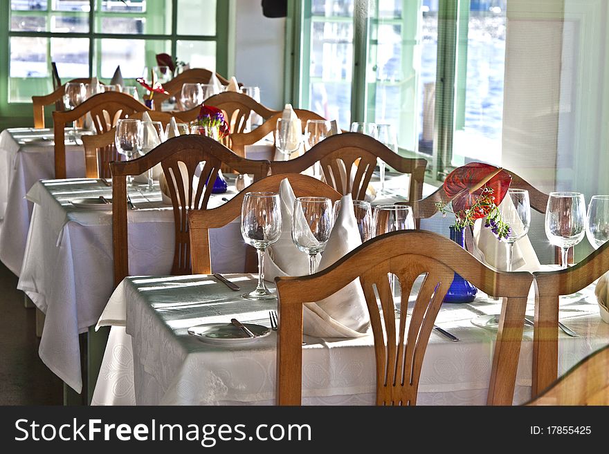 Table is set in a restaurant with glasses, flowers and tablecloth