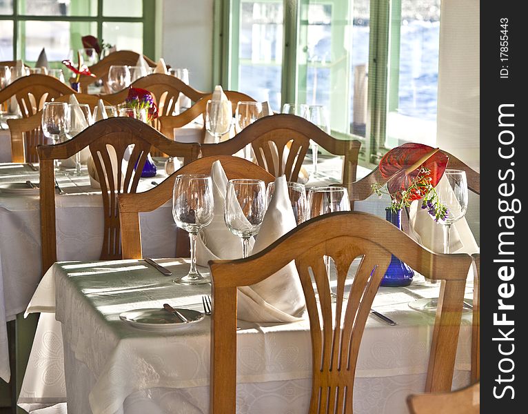 Table is set in a restaurant with glasses, flowers and tablecloth