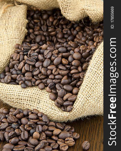 Roasted coffee beans with coffee bag on wooden surface