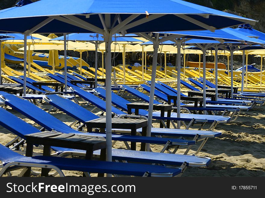 Empty blue and yellow sunbeds on sandy beach. Empty blue and yellow sunbeds on sandy beach