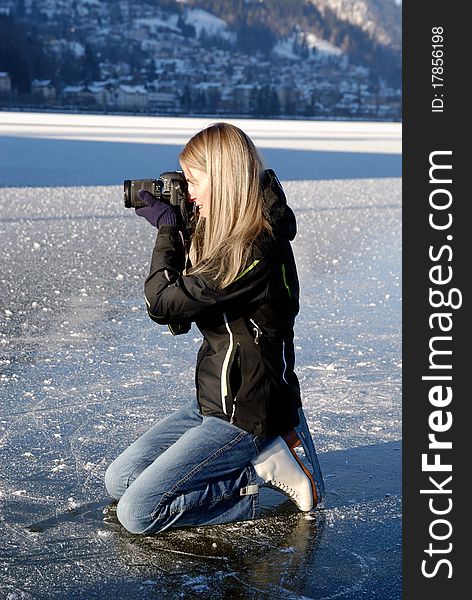 Woman kneeing on ice taking pictures on frozen lake. Woman kneeing on ice taking pictures on frozen lake