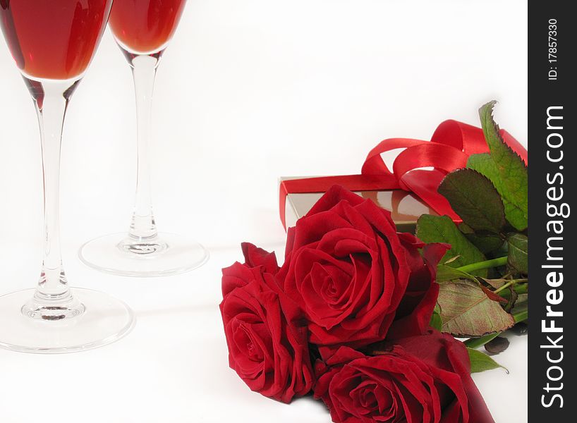 A bouquet of red roses with gift box and wine glass on white background. A bouquet of red roses with gift box and wine glass on white background