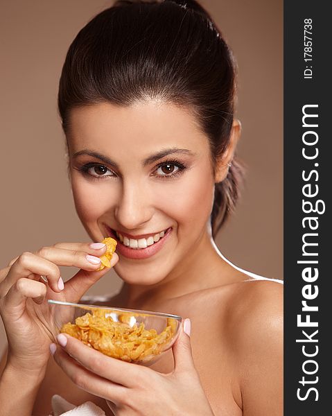 Portrait of a beautiful young woman eating cornflakes, isolated on beige. Portrait of a beautiful young woman eating cornflakes, isolated on beige