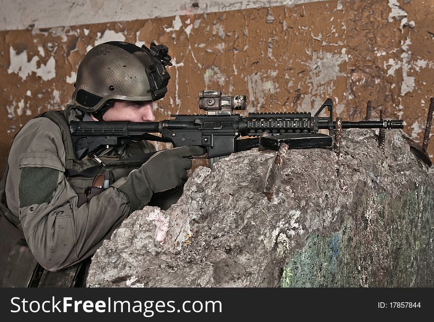 Young soldier in ruined building behind obstacle, aiming. air soft gun player. Young soldier in ruined building behind obstacle, aiming. air soft gun player.