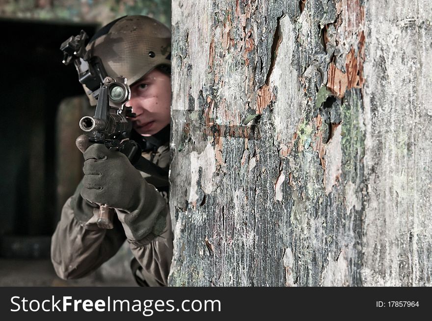 Young soldier in ruined building behind obstacle, aiming. air soft gun player. Young soldier in ruined building behind obstacle, aiming. air soft gun player.