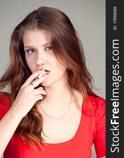 Beautiful caucasian women in red dress with a cigarette in teeth. Beautiful caucasian women in red dress with a cigarette in teeth