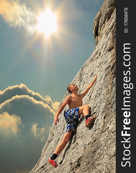 A guy climbs on a rock against the sky with a sunset. A guy climbs on a rock against the sky with a sunset