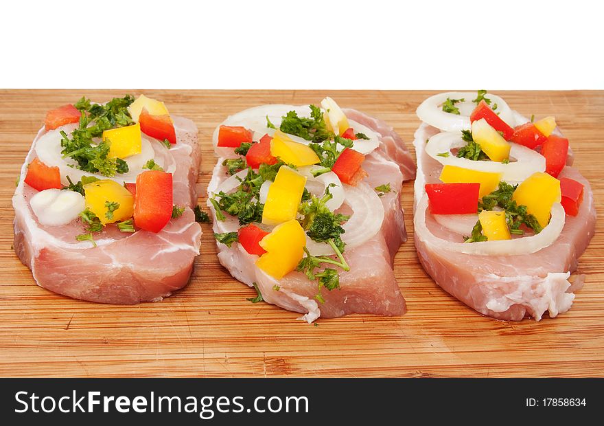 Raw pork chop with vegetables on a cutting board