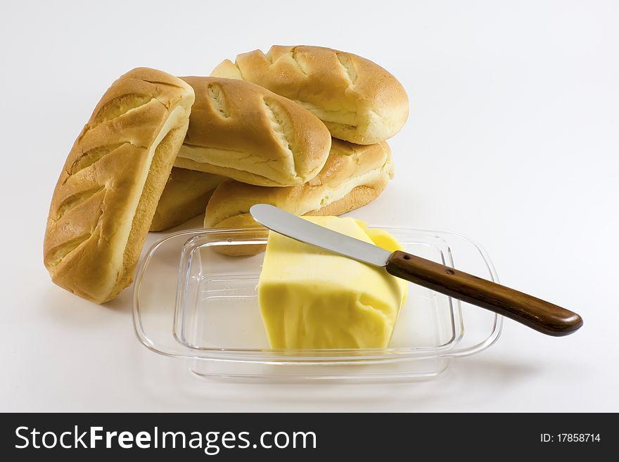 Bread rolls with butter and knife, on white background