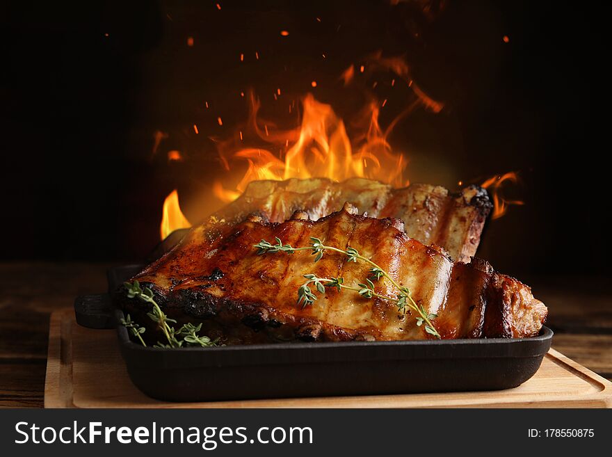 Tasty grilled ribs and flame on wooden board. Tasty grilled ribs and flame on wooden board
