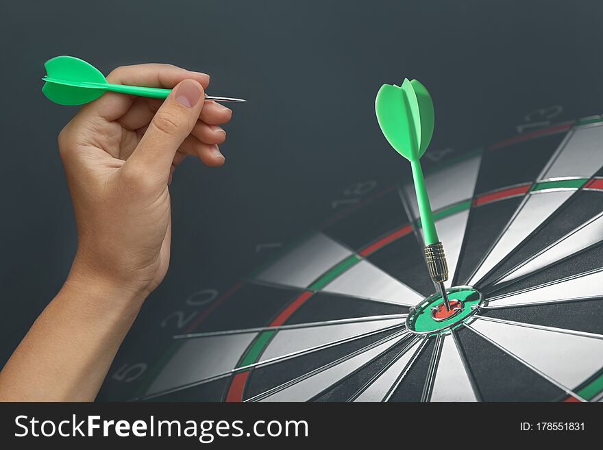 Woman with darts and board on grey background, closeup