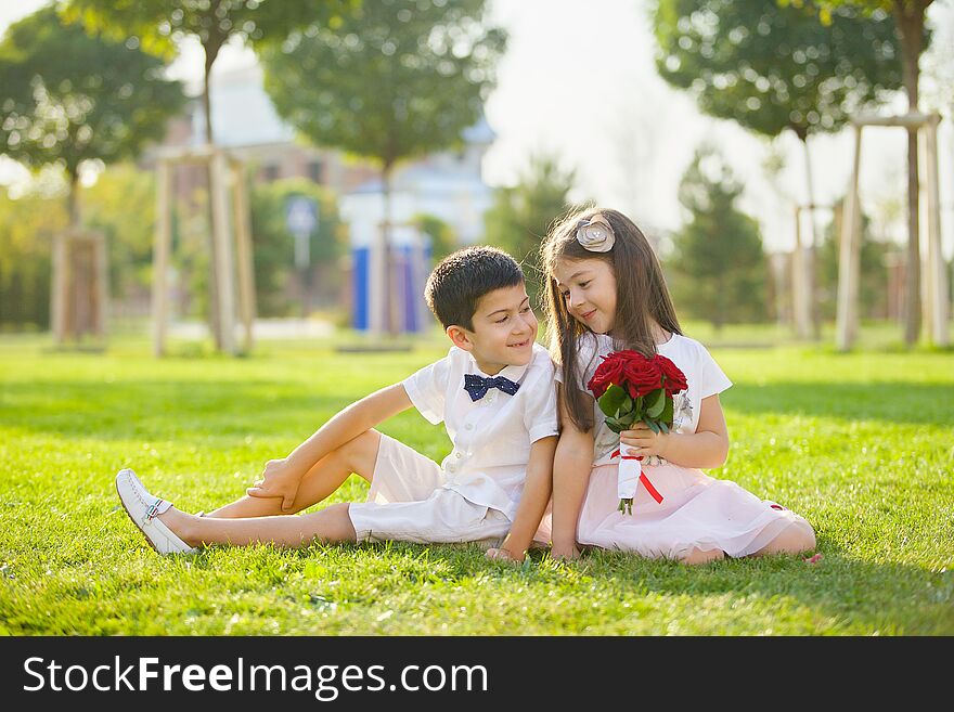 Two Beautiful Baby Brother And Sister Sitting In The Park In The Summer On The Grass