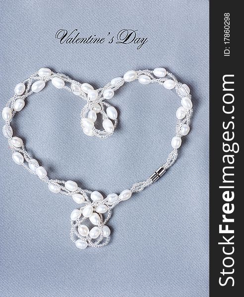 Heart-shaped string with pearls on a gray cloth. Heart-shaped string with pearls on a gray cloth