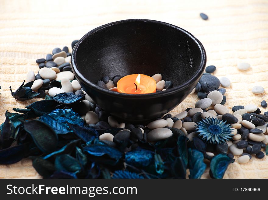 Orange candle in a black bowl and a blue potpourri. Orange candle in a black bowl and a blue potpourri