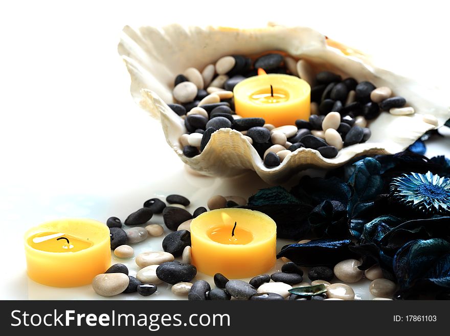 Closeup of yellow candles, blue potpourri and seashell on a white background. Closeup of yellow candles, blue potpourri and seashell on a white background