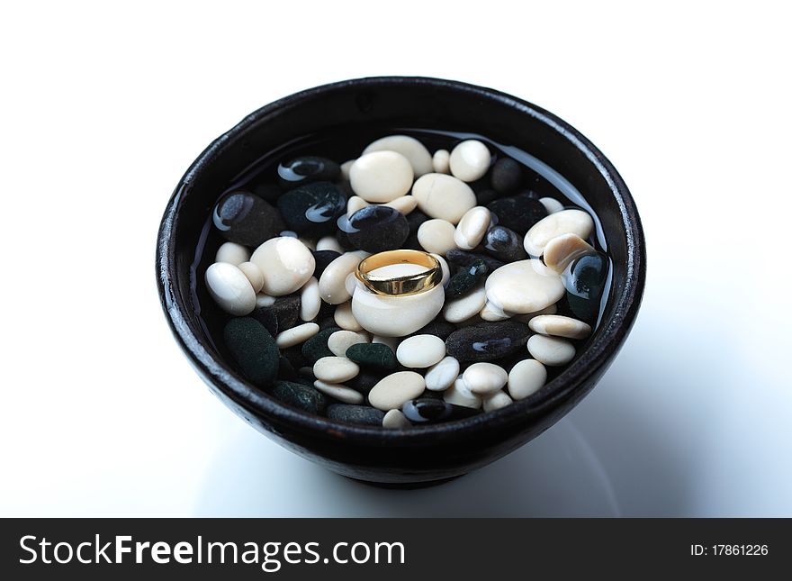 Golden wedding ring placed in a bowl with water and small rocks. Golden wedding ring placed in a bowl with water and small rocks