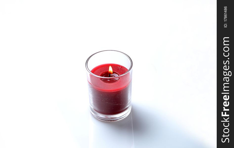 Small red candle in a glass holder on a white background. Small red candle in a glass holder on a white background