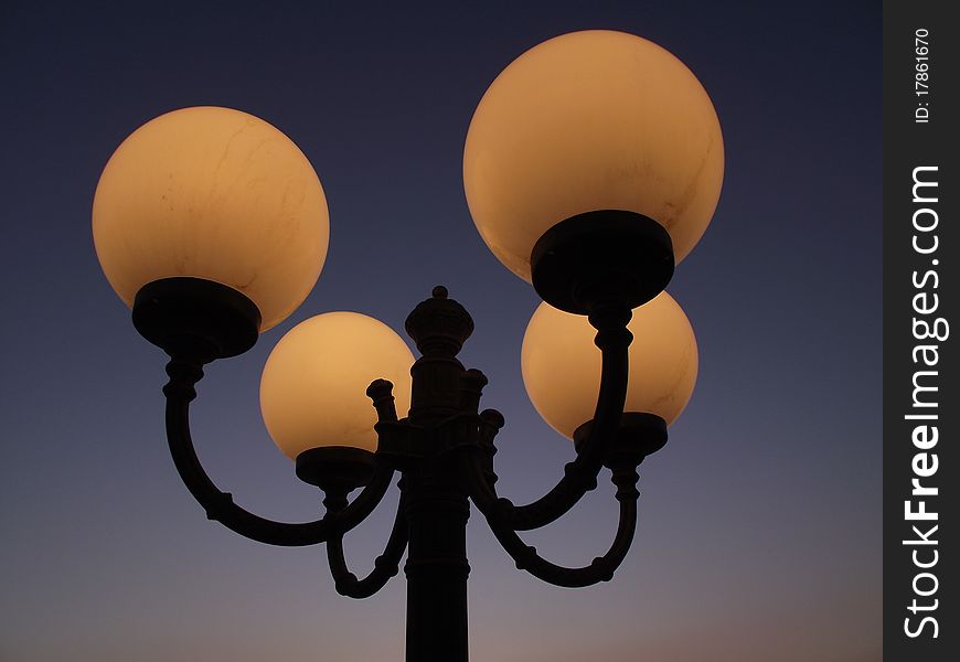 Streetlamps lightning the first evening in a clear sky. Streetlamps lightning the first evening in a clear sky.